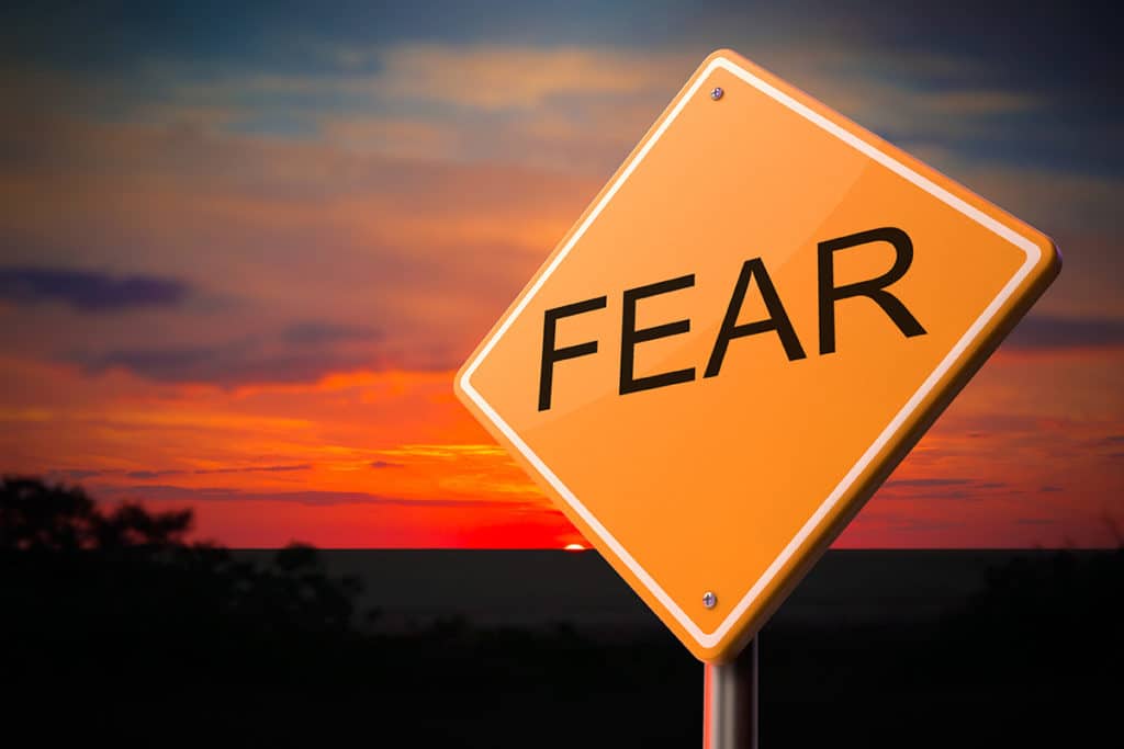 sign post with the word 'fear' on it against a red sunset