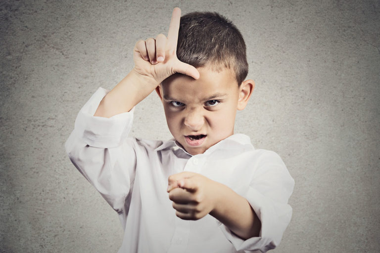 Angry child, signing 'L' for loser on their forehead, and pointing at the camera.
