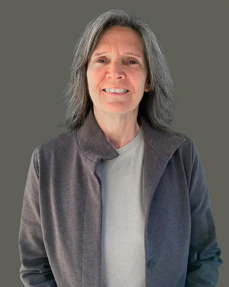 "Dignified three-quarter portrait of Karen Lee Morton, MA, an independent conflict systems specialist and Canadian public sector consultant, standing against a neutral slate gray background."
